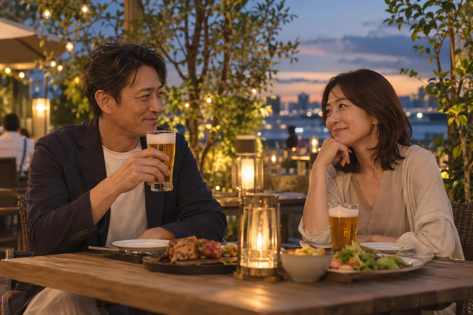 夕暮れのビアガーデンで、食事と会話を楽しむ40代半ばの男女。